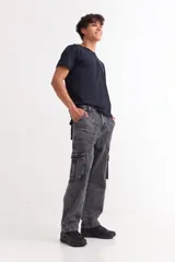 Pantalón tipo cargo de corte baggy, confeccionado en denim con efecto lavado ácido en tono gris oscuro. Presenta bolsillos laterales tipo cargo, bolsillos frontales y traseros, y cierre frontal con botón y cremallera.
