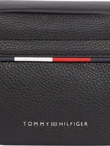 Riñonera negra de poliuretano granulado con cierre de cremallera, correa ajustable de textil trenzado con cierre de apertura fácil, bolsillo interior con cremallera, cinta distintiva y logo metálico de Tommy Hilfiger en la parte delantera.