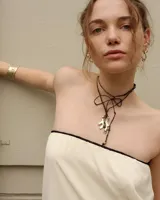 Collar con dije de bronce macizo con forma orgánica irregular, similar a un coral, suspendido de un cordón negro de seda natural anudado.