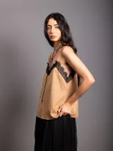 Top de breteles finos estilo camisola, confeccionado en material símil gamuza color negro, con detalle de encaje en el escote y costura vertical frontal.