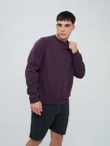 Buzo de felpa bordó, estilo relaxed, con cuello redondo y mangas raglán. Presenta puños y dobladillo acanalados, y una pequeña etiqueta con el logo de Umbro en el lateral inferior.