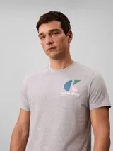 Remera gris melange de manga corta con cuello redondo, confeccionada en algodón regenerativo. Cuenta con un pequeño estampado gráfico del monograma y la inscripción de la marca en el pecho.