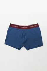 Boxer de algodón color azul, con elástico ancho color bordó que lleva la inscripción "Uniform" en blanco.