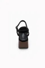 Sandalias de plataforma con cuña efecto madera y capellada de gamuza negra, con tira ancha en la parte delantera y tira ajustable alrededor del tobillo.