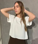 Blusa blanca de corte suelto y mangas cortas con doblez.