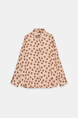 Camisa de corte clásico confeccionada en tela satinada, con estampado de lunares en contraste. Presenta cuello solapa, cierre frontal con botones y mangas largas con puños rectos.