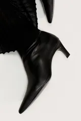 Botines de cuero negro con caña elástica, punta fina y taco fino de altura media.