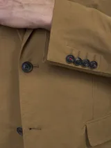 Blazer color marrón claro, de corte clásico, con solapas de muesca, cierre de dos botones, bolsillo en el pecho y bolsillos laterales con solapa.