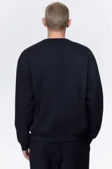 Buzo azul marino de tejido de mezcla de algodón de peso medio con interior cepillado suave. Modelo con cuello redondo ribeteado, hombros caídos y remate acanalado ancho en puños y bajo. Corte holgado.