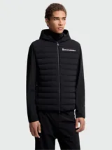 Campera Moncler Grenoble acolchada con capucha y cierre frontal, color negro, con diseño híbrido que combina panel frontal matelasseado con mangas y espalda de tejido liso técnico.
