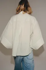 Camisa de mezcla de algodón de corte oversize y diseño asimétrico en tono azul, con cuello solapa, mangas tipo kimono por debajo del codo y cierre lateral con botones.