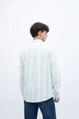 Camisa de manga larga color blanco con rayas verticales finas en verde menta, corte regular fit, cuello clásico y bolsillo en el pecho.