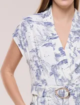Enterito largo color blanco con estampa ilustrada en azul estilo Toile de Jouy, escote en V cruzado, mangas cortas caídas, bolsillos laterales, pantalón amplio wide leg y cinturón incorporado con hebilla metálica.
