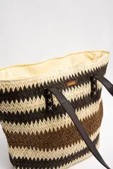 Bolso tipo tote de diseño trenzado con patrón de rayas en tonos marrones y beige, doble asa larga de material sintético oscuro y placa metálica con logo.
