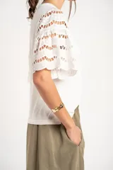 Remera blanca con mangas cortas abullonadas de encaje con diseño perforado, cuello redondo y corte oversize.