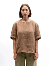 Remera de lino de corte holgado y relajado, con mangas cortas y cuello redondo. Presenta un diseño minimalista con detalle de botones en la espalda.