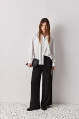 Camisa celeste de calce relajado, con cuello camisero, bolsillo aplicado en el pecho y mangas largas con puños abotonados. Cuenta con lazos ajustables en los laterales para fruncir y regular la silueta.