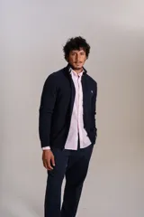 Cardigan de punto color azul marino, con cuello alto, cierre frontal completo y puños acanalados. Presenta el logo de la marca bordado en el pecho.
