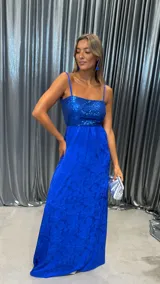 Vestido largo azul eléctrico, con corpiño de lentejuelas y falda larga con textura floral en relieve. Posee tirantes finos y escote recto.
