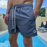 Short de baño negro con cintura elástica y cordón ajustable bicolor. Presenta un parche circular con logo en la parte inferior de la pierna.
