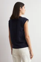 Remera azul marino de manga corta, con corte holgado y detalle de botones metálicos en los laterales.