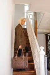 Bolso de mano tipo shopper marca Amadea, confeccionado en cuero con acabado desgastado. Presenta detalles de costuras decorativas verticales, correas con hebillas metálicas doradas y logo grabado al frente.