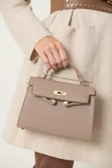 Cartera tipo bolso de mano color tostado, con diseño estructurado, asa superior corta y cierre frontal con broches metálicos dorados.