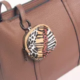 Cartera tipo tote de cuero sintético en color marrón, con textura granulada, doble asa de hombro y un pequeño monedero circular colgante con estampado animal print.