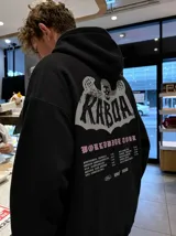 Canguro de felpa gris melange con capucha, manga larga y estampa trasera de estilo rockero con tipografía y calavera.