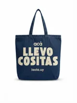 Cartera tipo tote bag de denim azul con doble asa de hombro y estampado frontal en color beige con la frase "acá llevo cositas".