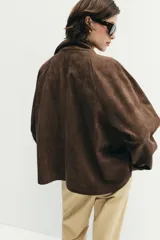 Chaqueta de tejido efecto ante color marrón, con cuello alto, cierre frontal con cremallera y botones a presión, manga larga y bolsillos de plastrón con solapa en el delantero.