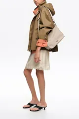 Bolso shopper mediano de mano Bimba y Lola color marrón, confeccionado en poliamida con detalles en cuero y herrajes metálicos dorados. Cuenta con doble asa de mano, correa de hombro ajustable de lona beige, cierre superior con cremallera y logo impreso en dorado al frente.