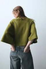 Jersey de punto color verde oliva, con cuello subido y mangas anchas tipo acampanadas.