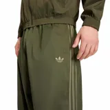 Pantalón Adidas Adicolor Sarga SST de corte holgado y pernera ancha, color verde militar. Presenta cintura elástica con cordón ajustable y las clásicas tres tiras de la marca a lo largo de los laterales. Incluye el logo del trifolio bordado en una pierna.