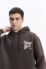 Canguro con capucha de algodón color celeste, con estampa gráfica en la espalda que incluye flores y la frase 'Grow Back'. Presenta un parche pequeño en la manga y corte regular.