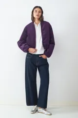 Jean de tiro medio, corte barrel con ajuste relajado en la parte superior, diseño clásico de cinco bolsillos, con cierre frontal de cremallera y botón metálico.