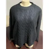 Sweater de punto color blanco marfil, con diseño de trenzas frontales, cuello redondo y mangas largas con puños elásticos acanalados.