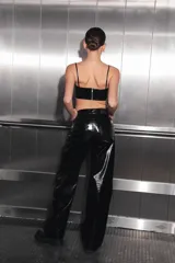 Pantalón negro de charol con tiro medio alto, botón metálico níquel, badana de RENÉE en cintura y bolsillos traseros.