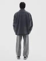 Camisa de denim de manga larga con cuello clásico, cierre frontal de botones y diseño oversize con lavado tipo washed.