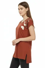 Remera de algodón negra, de corte holgado, con cuello redondo a la base y detalle de estampado floral en el hombro izquierdo.