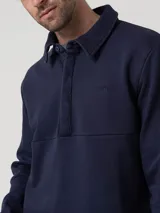 Buzo de algodón orgánico azul marino con cuello camisero, manga larga y medio cierre abotonado con solapa tapada.
