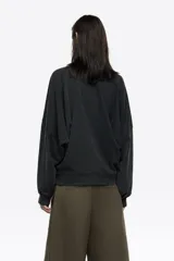 Buzo de algodón color negro con efecto gastado, corte globo y mangas largas ranglán. Presenta un logo bordado discreto en el pecho.