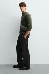 Bandolera negra con correa fina ajustable, cierre con solapa imantada, bolsillo interno y detalle de borla lateral.
