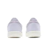 Championes New Balance modelo T500, color lila con la clásica "N" en blanco en los laterales y detalles metalizados en el talón. Combinan gamuza y malla, con una suela de goma blanca.