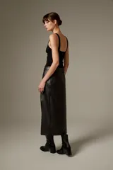 Falda midi de eco-cuero negro con corte recto y tajo lateral, incluye cinturón con hebilla metálica.
