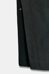 Capa de corte amplio confeccionada en hilatura con lana, con cuello alto y mangas tipo capa. Presenta cierre frontal con cremallera y botones ocultos por solapa, bolsillos delanteros y bajo asimétrico con aberturas laterales.