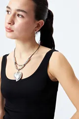 Collar con doble cadena, una de cuero negro y otra de eslabones plateados, con dije de corazón plateado.