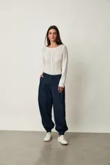 Pantalón tipo jean azul oscuro, de corte slouchy con pinzas en la cintura, bolsillos laterales y puños fruncidos con elástico en los tobillos.