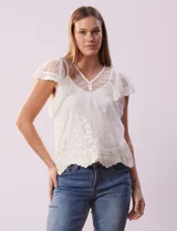 Blusa de dos piezas color blanco, marca Cupio. La pieza superior es de tul bordado con escote en V con botones, manga corta amplia y ruedo con puntilla bordada. Incluye forro interno a tono.
