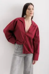 Camisa blanca de algodón, de corte holgado, con cuello clásico, mangas largas con puños anchos y un bolsillo de parche en el lateral.